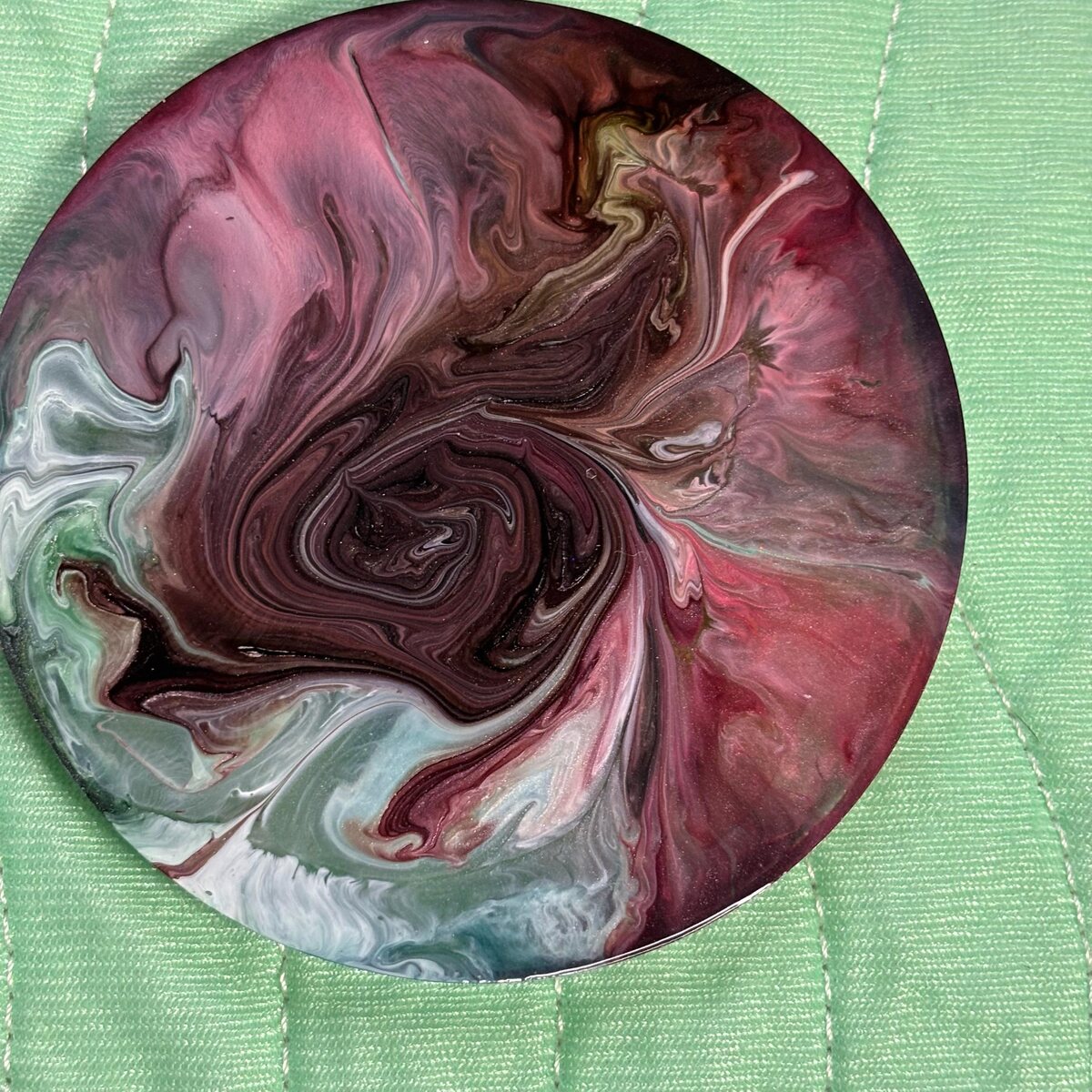 Round burgundy resin coaster with cream and gray swirls
