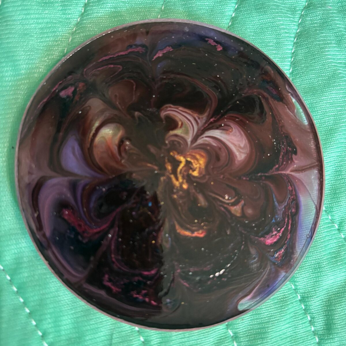 Round dark rose resin coaster with black, copper, and pink swirls