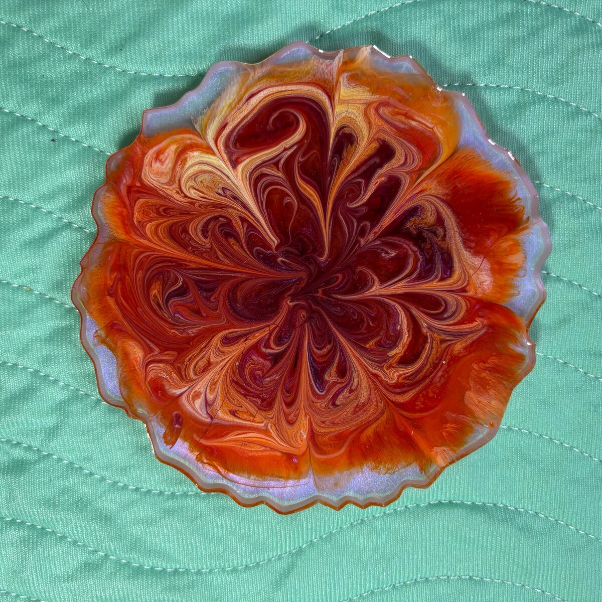 Orange scalloped resin dish with flower-like swirl pattern