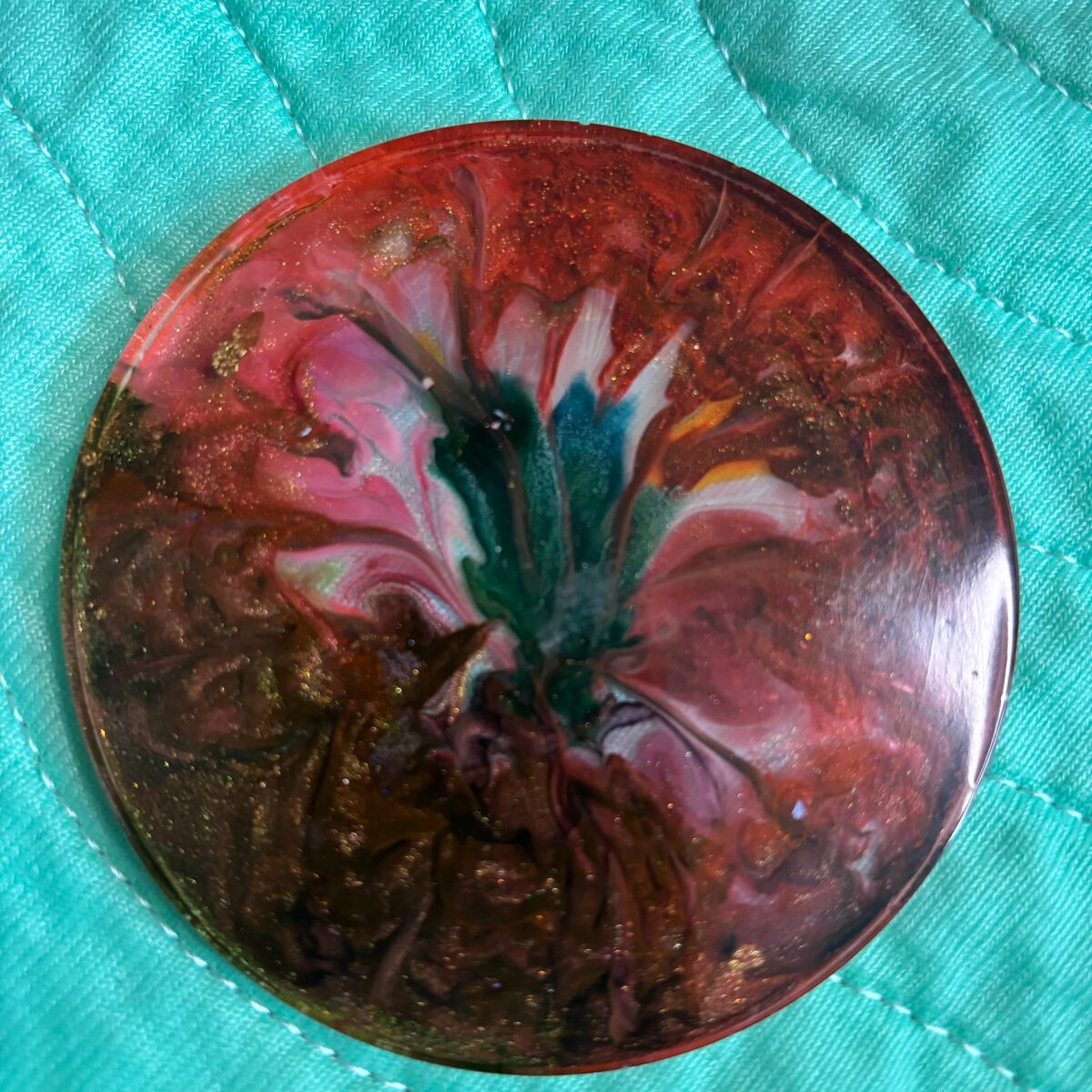 Round red and teal resin coaster with dark shimmer