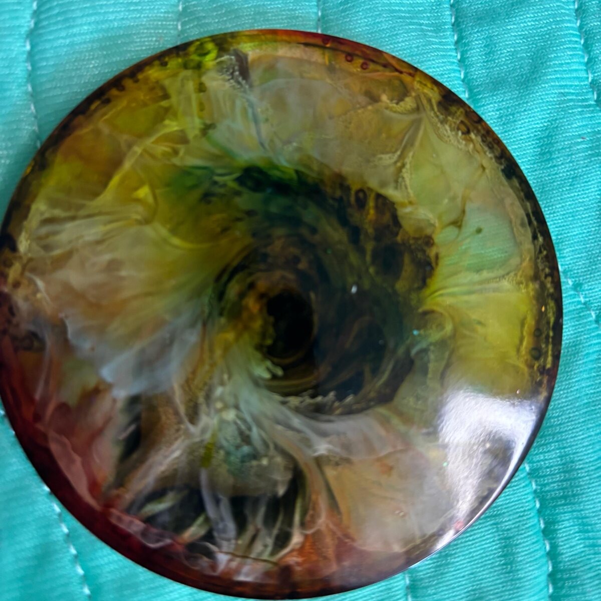 Round smoky yellow resin coaster with dark center swirl